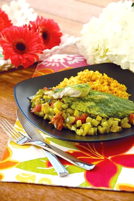 Tilapia al cilantro servida sobre arroz dorado con verduras